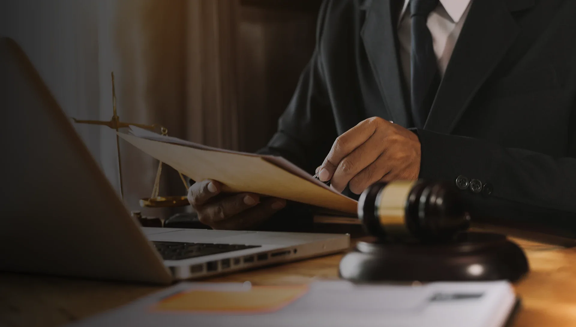 Lawyer reviews documents with a gavel and laptop on the desk.